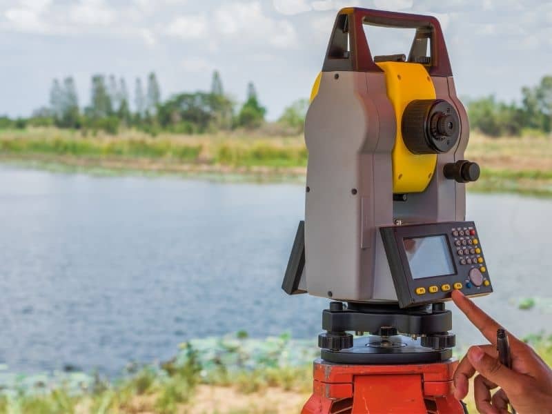 Survey equipment set near a riverfront area to measure land elevations before site reuse planning.
